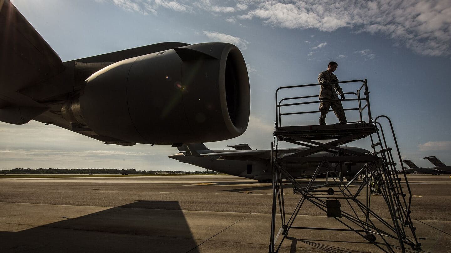 A maintainer on a work stand beside a large jet engine nacelle