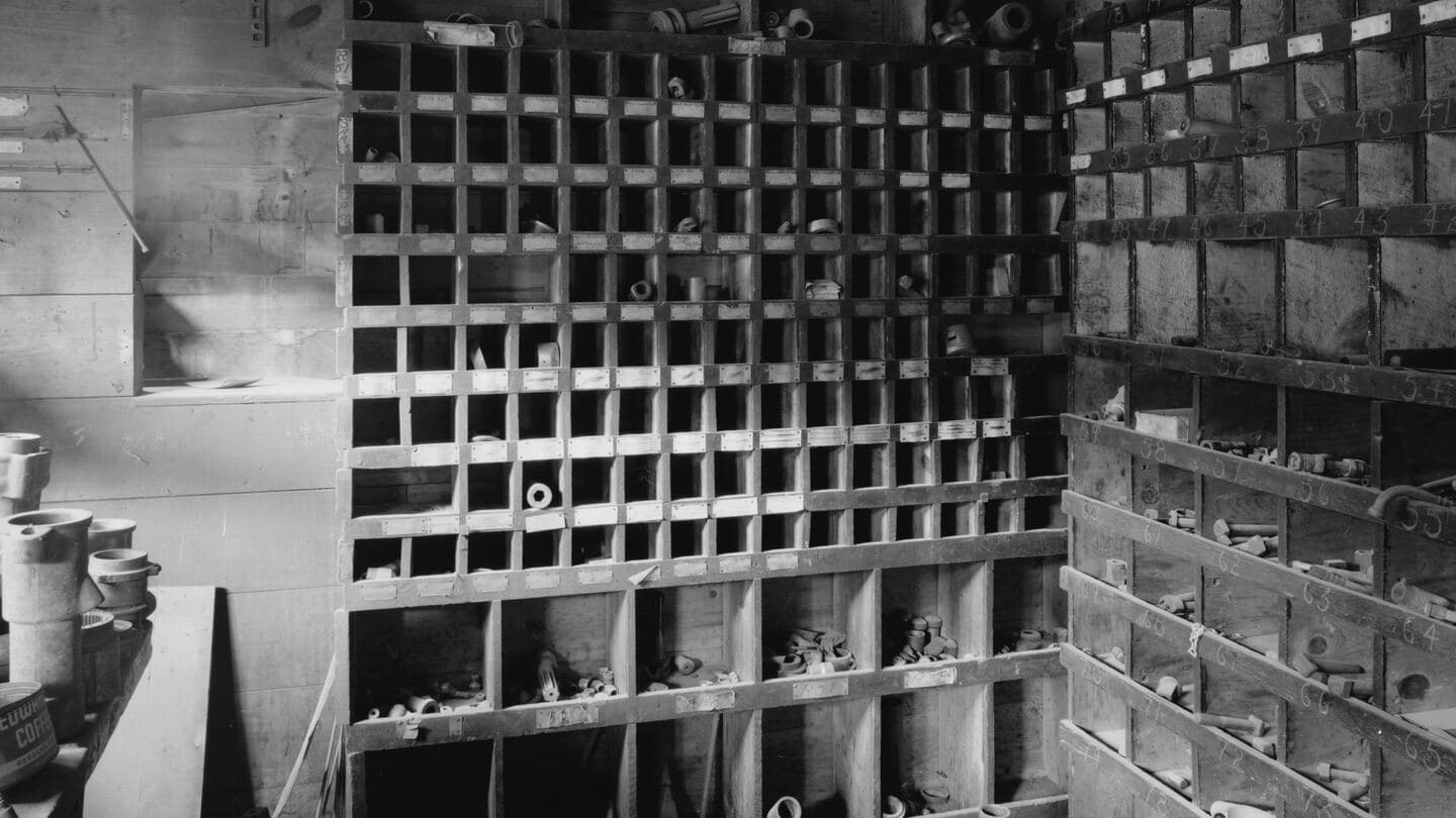 Walls of wooden pigeonhole parts bins in an old mill compressor room, black and white