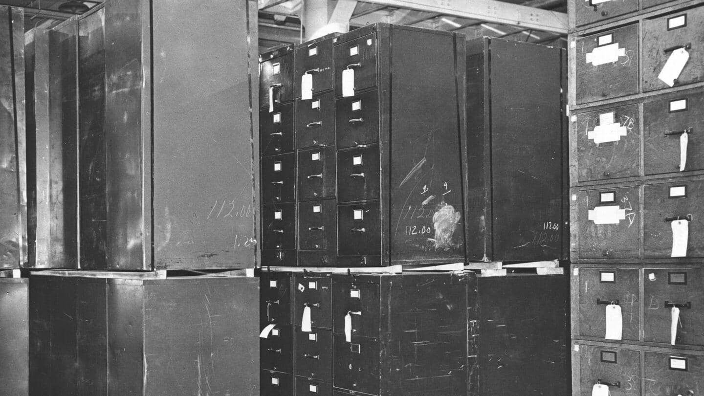Rows of worn steel filing cabinets stacked two high in a federal records storage area