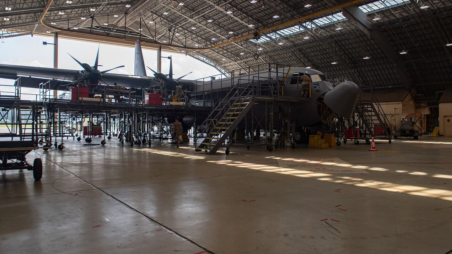 A transport aircraft under maintenance inside a large hangar