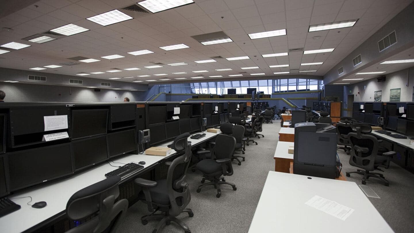 A modern, empty control room with rows of consoles