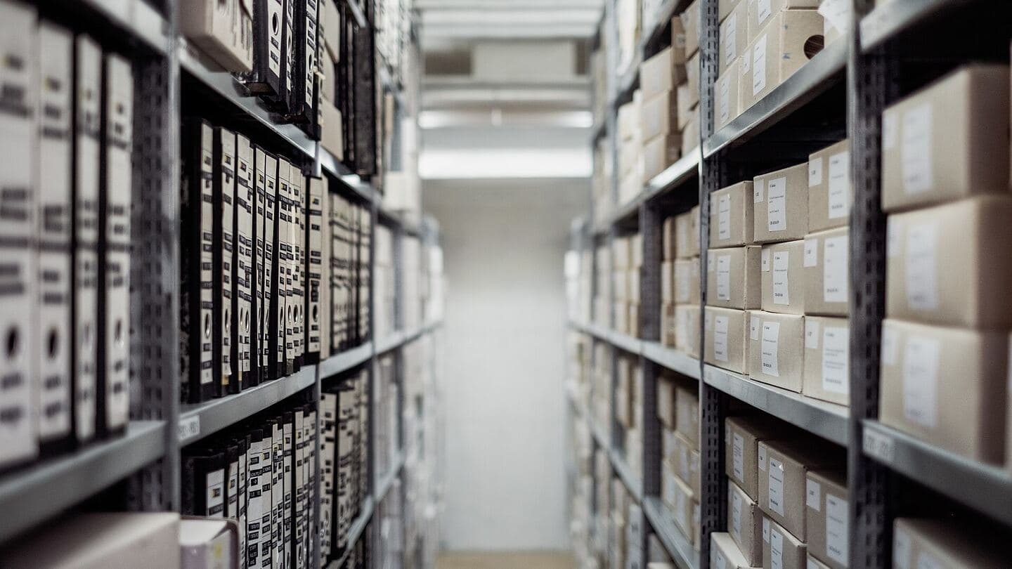 Archive shelves of identical labeled binders and storage boxes lining a narrow aisle