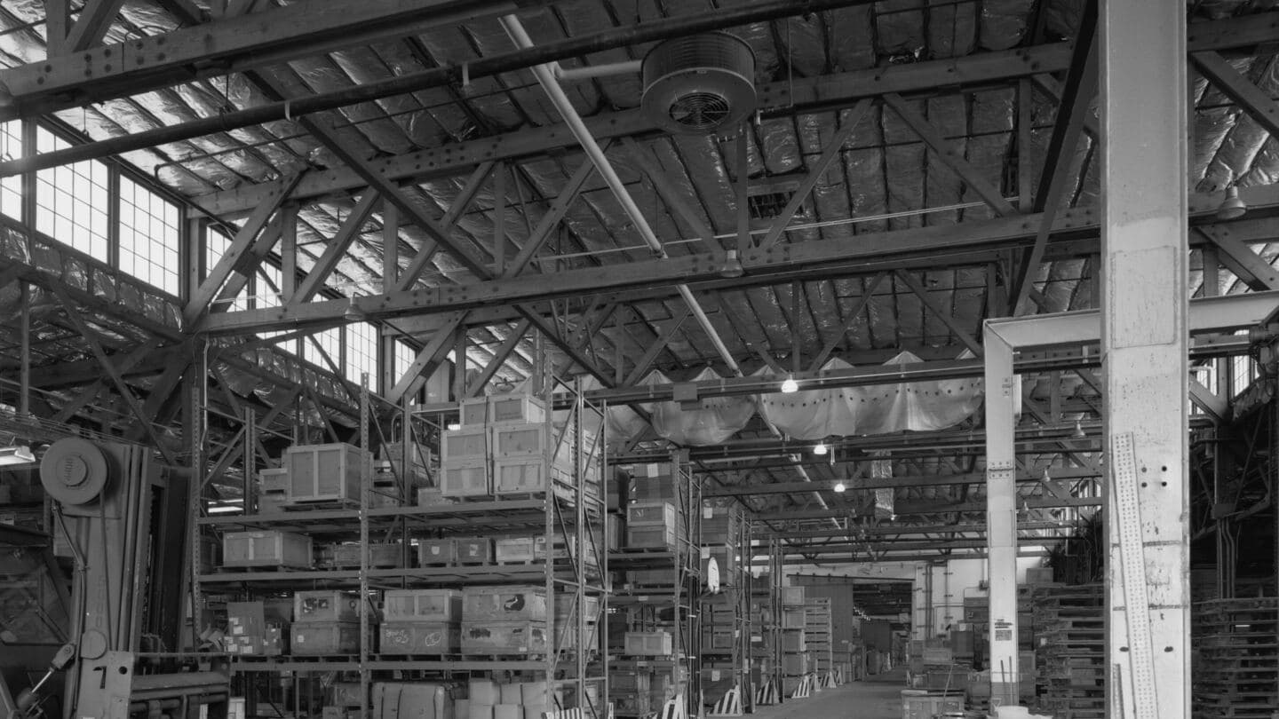 Interior of a large wood-truss depot warehouse with crates on tall steel racks