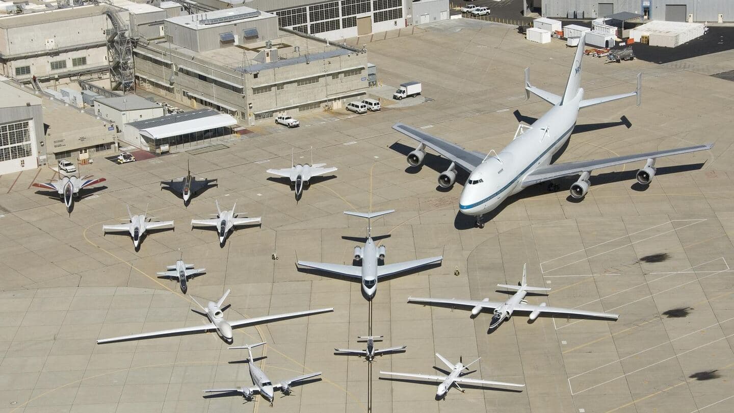Aerial view of military jets and large transport aircraft parked together on one flight-line ramp