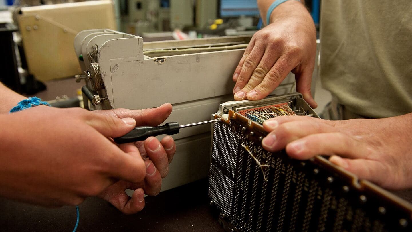 Hands working on an avionics unit at a repair bench