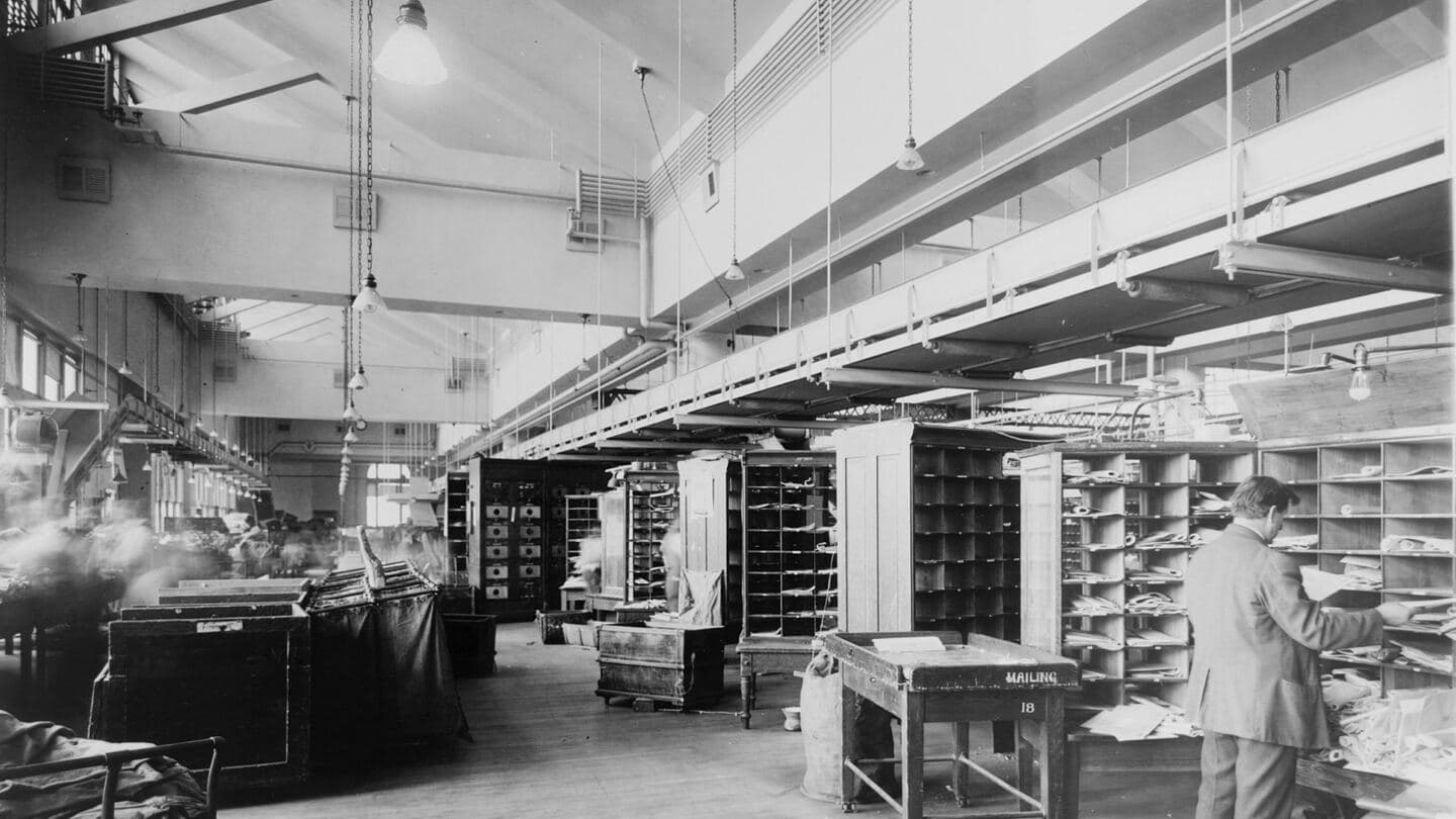 A post office mail sorting room lined with pigeonhole sorting cases, 1920s