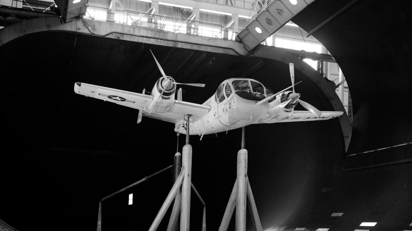 Black-and-white photo of an aircraft model mounted in a wind tunnel