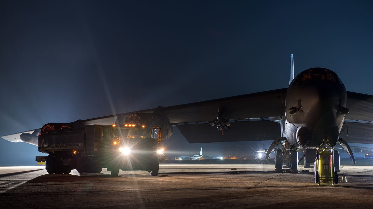 A fuel truck services a B-52 bomber on the flight line at night under floodlights