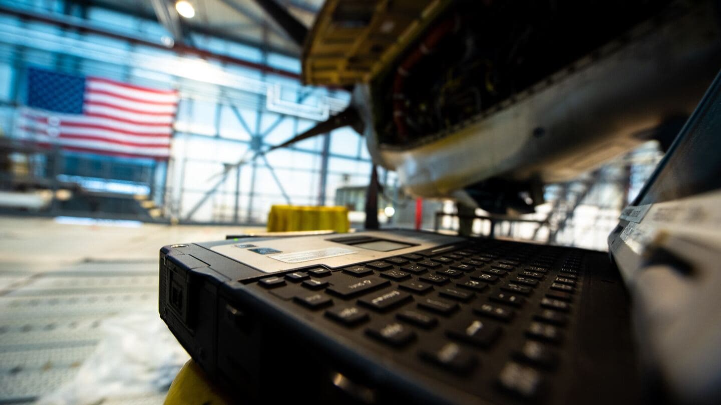 A rugged laptop on a stand in an aircraft maintenance hangar