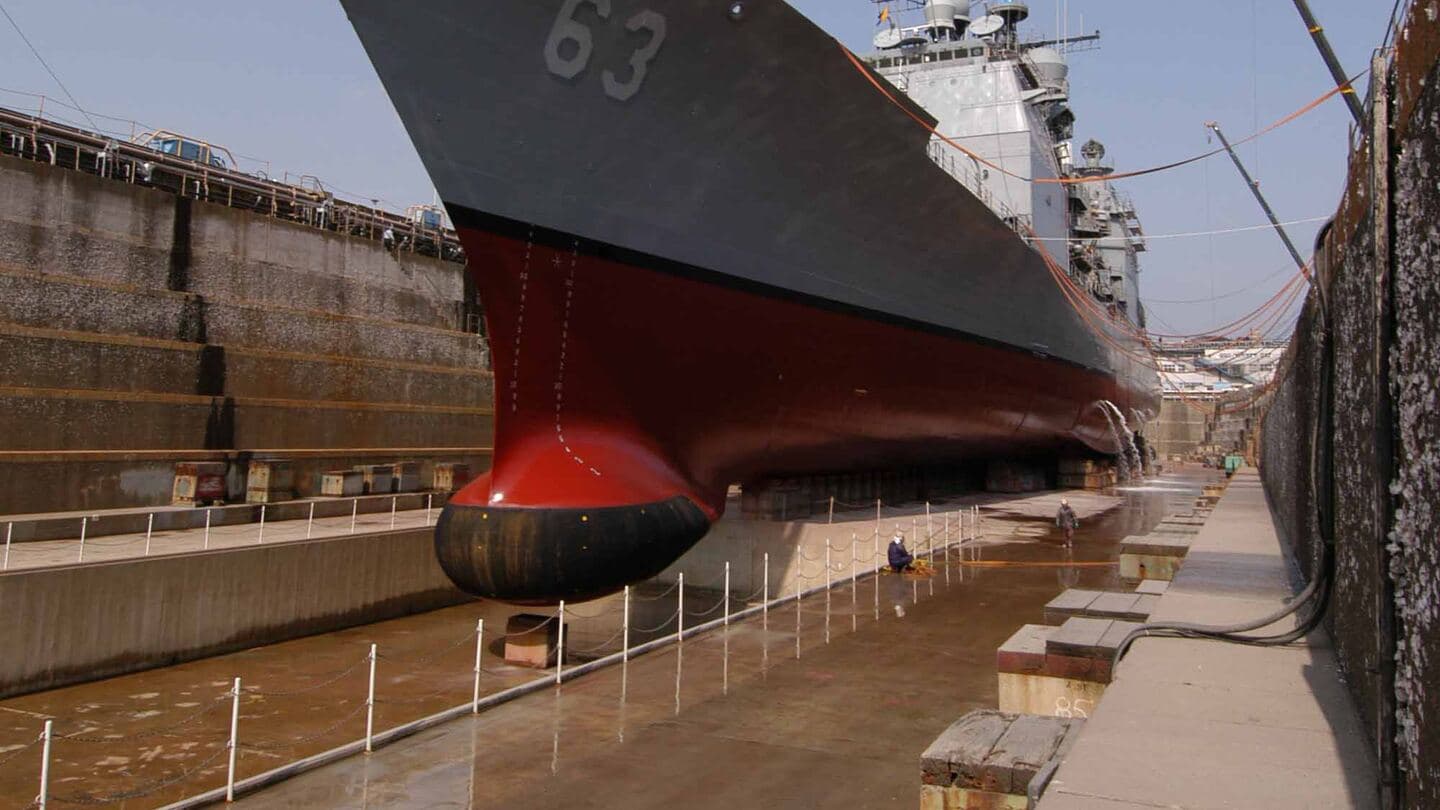 A guided-missile cruiser's bow and sonar dome high and dry in a graving dock