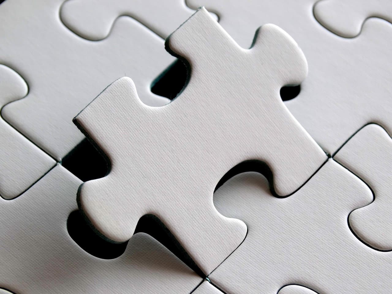 A single jigsaw piece being lowered into the one gap in an otherwise complete puzzle